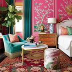 Decorative living room with pink walls, teal chair, a red asian inspired rug, and floral accents.